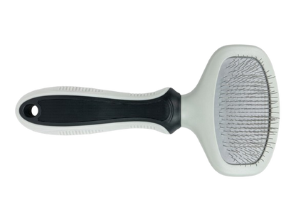 Pet grooming brush with black handle and white bristle head on a white background